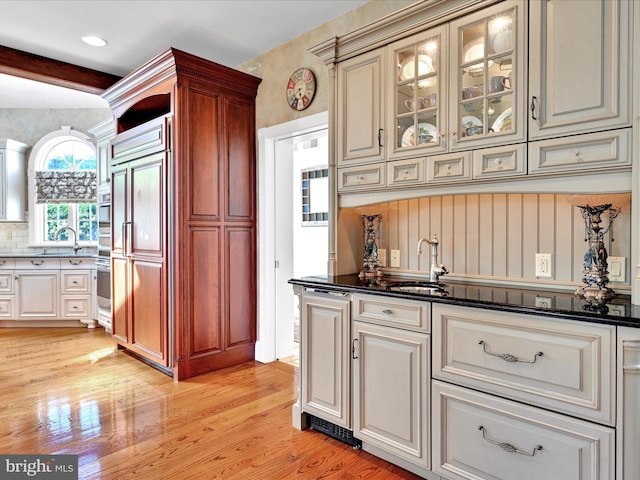 kitchen featuring stainless steel oven, paneled fridge, sink, beam ceiling, and light hardwood / wood-style floors