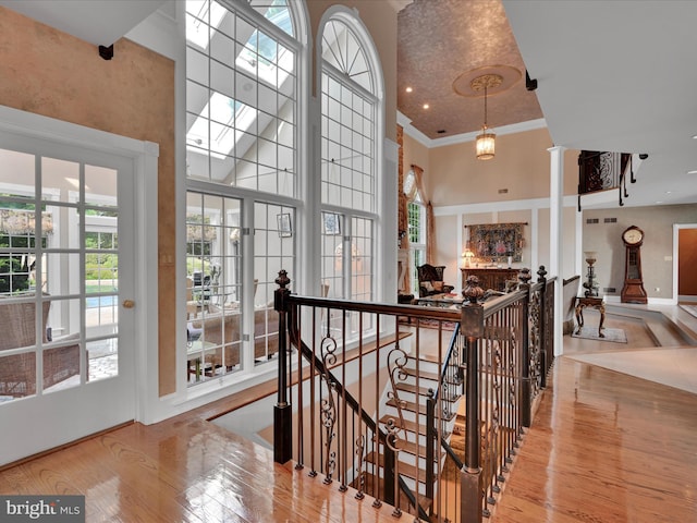 stairway featuring hardwood / wood-style floors, crown molding, a high ceiling, and a skylight