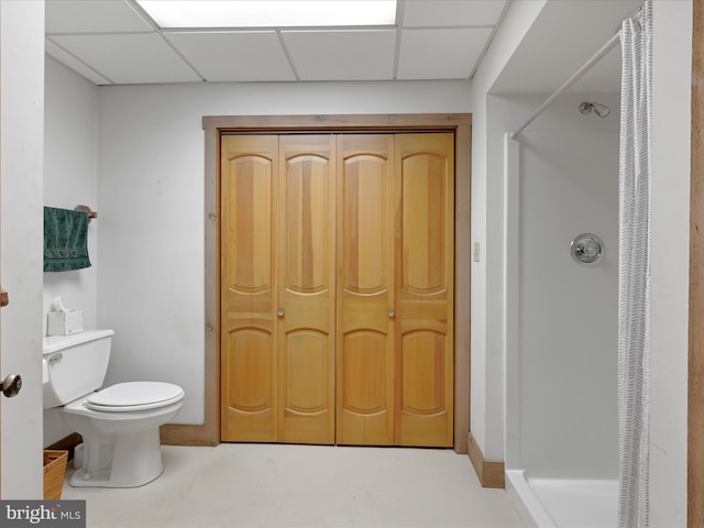 bathroom featuring a shower, a drop ceiling, and toilet