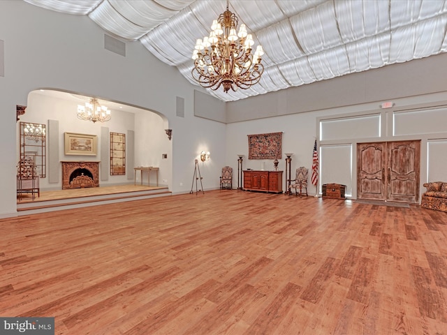 unfurnished living room with a high ceiling and light wood-type flooring