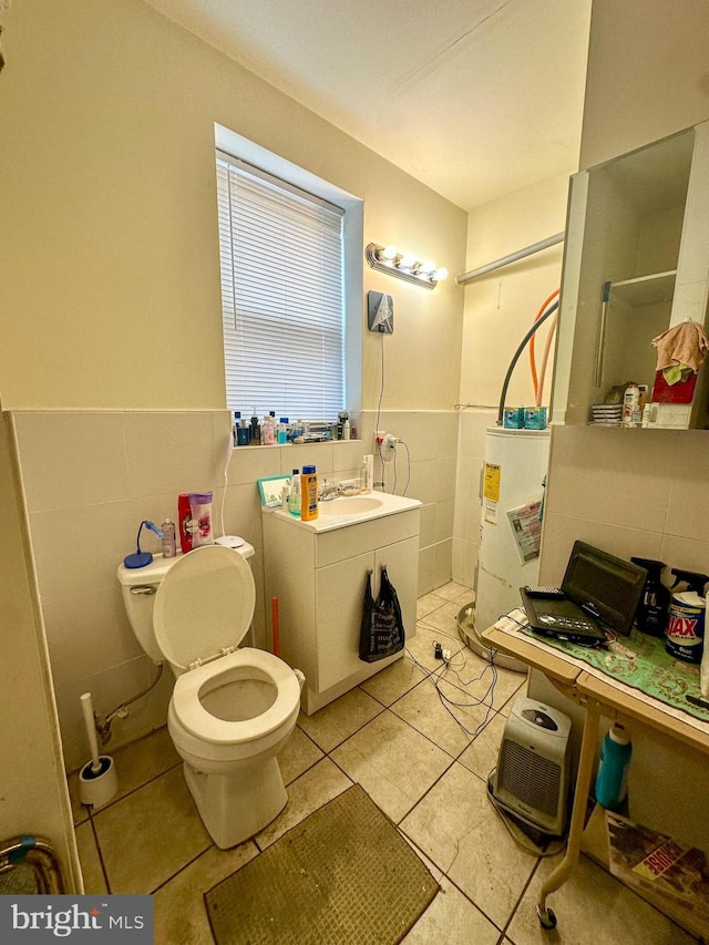 bathroom featuring sink, gas water heater, tile patterned floors, toilet, and tile walls