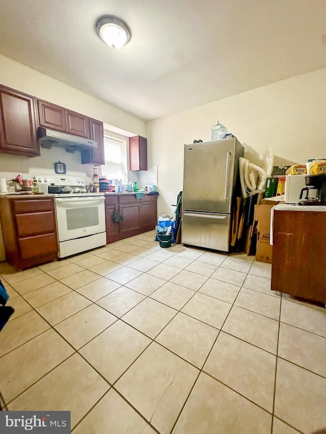 kitchen featuring white electric range oven, light tile patterned floors, sink, and stainless steel refrigerator