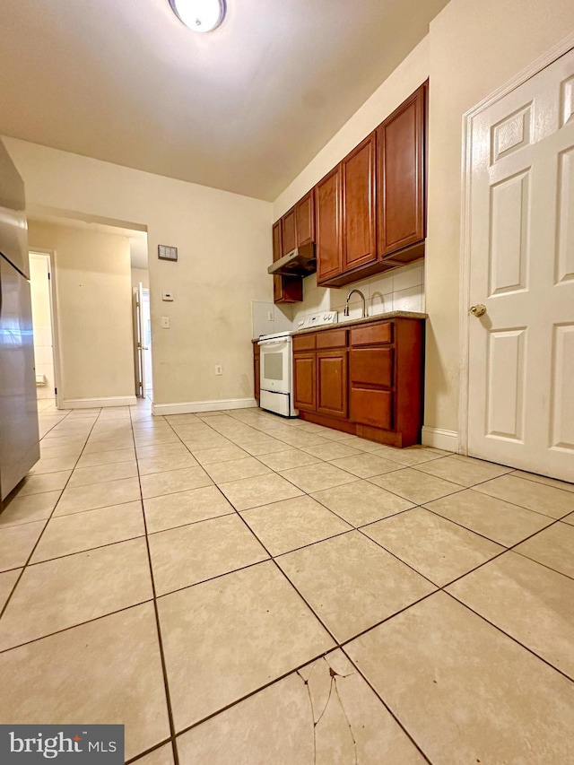 kitchen with white range with electric stovetop, stainless steel fridge, and light tile patterned floors