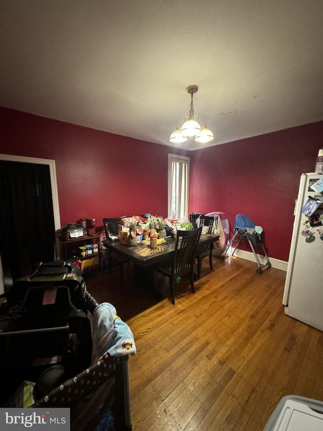 dining area with hardwood / wood-style flooring and an inviting chandelier