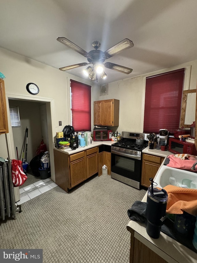 kitchen with ceiling fan, light tile patterned floors, sink, and gas range