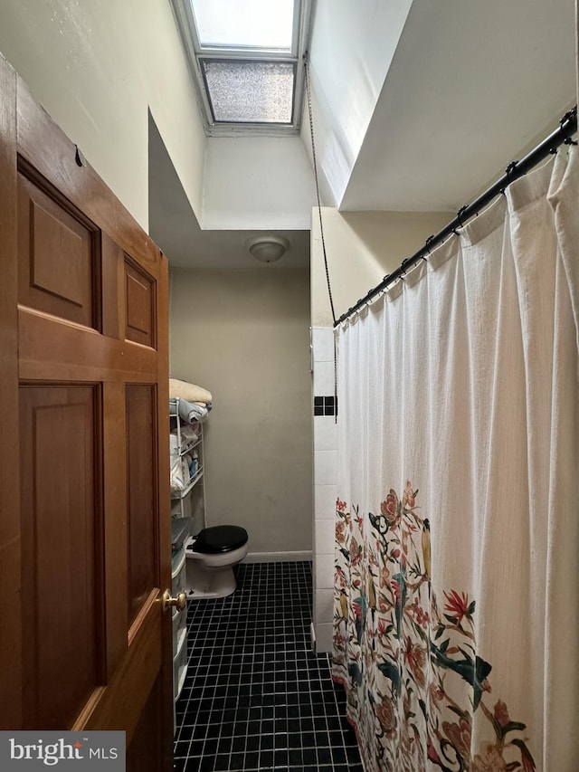 bathroom featuring tile patterned flooring, a shower with curtain, a skylight, and toilet