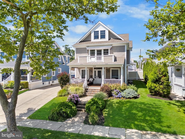 view of front of home with a balcony, a front yard, and covered porch