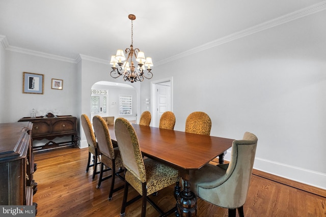 dining space with hardwood / wood-style flooring, ornamental molding, and a notable chandelier