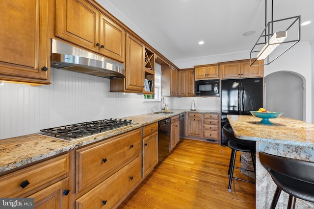 kitchen with pendant lighting, sink, black appliances, crown molding, and light stone countertops