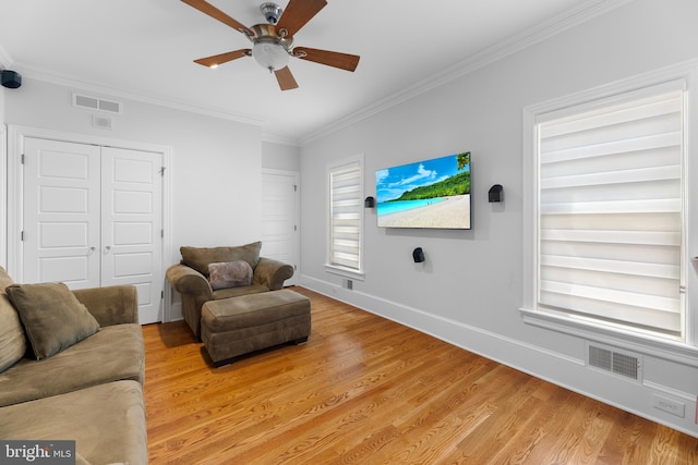 living room with ornamental molding, plenty of natural light, ceiling fan, and light wood-type flooring