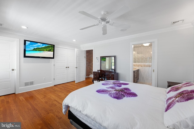 bedroom featuring wood-type flooring, ornamental molding, ceiling fan, ensuite bath, and a closet