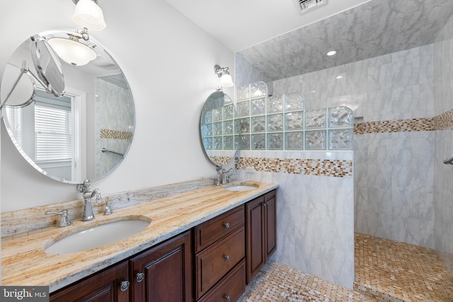 bathroom with vanity, tile patterned flooring, tile walls, and a tile shower