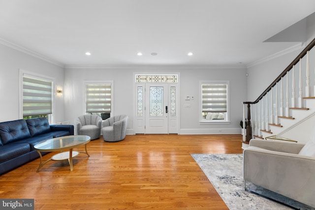 living room featuring crown molding, a healthy amount of sunlight, and light hardwood / wood-style flooring