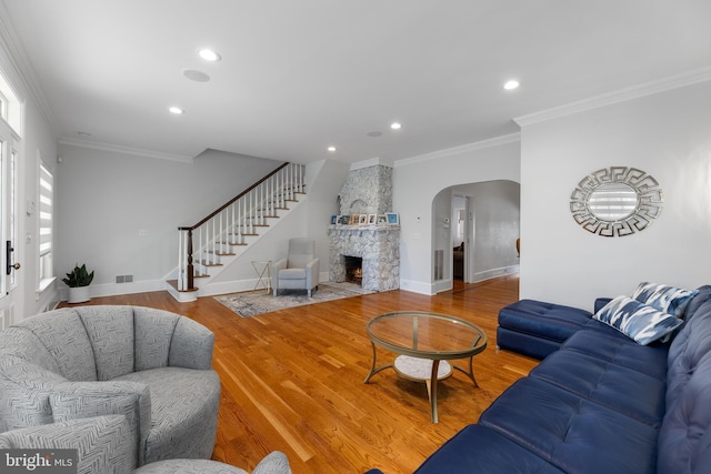 living room with ornamental molding, a fireplace, and hardwood / wood-style floors