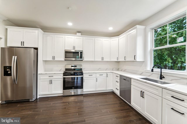 kitchen with appliances with stainless steel finishes, a healthy amount of sunlight, white cabinetry, and sink