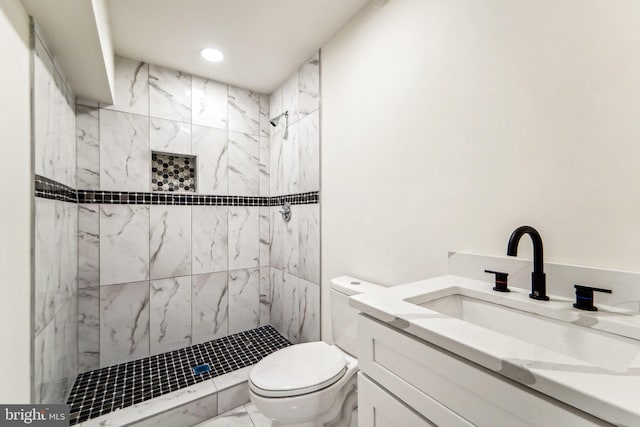 bathroom with toilet, vanity, and a tile shower