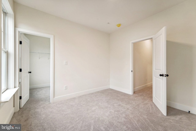 unfurnished bedroom featuring light colored carpet, a closet, and a spacious closet