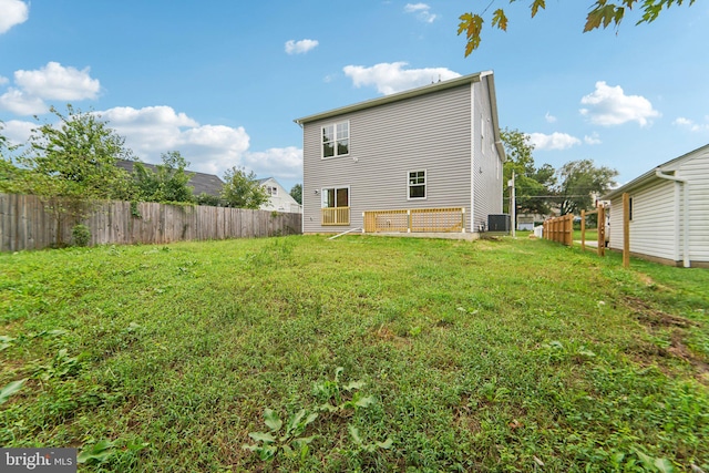 back of property featuring central air condition unit and a yard