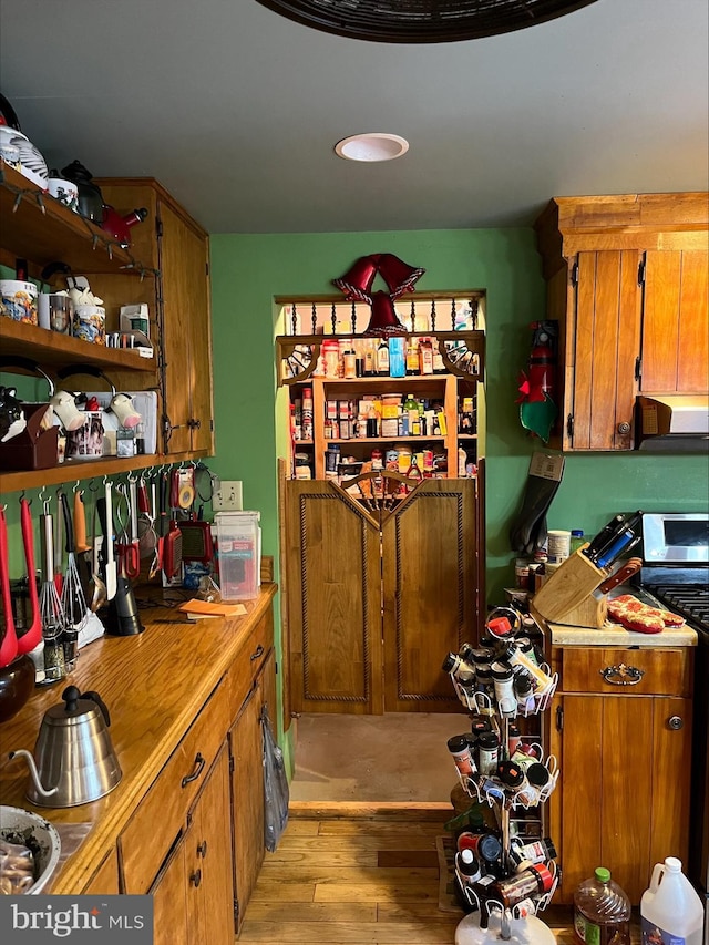 kitchen with ventilation hood, light wood-type flooring, and stainless steel electric range oven