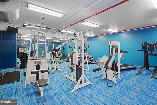 exercise room with a textured ceiling and carpet floors