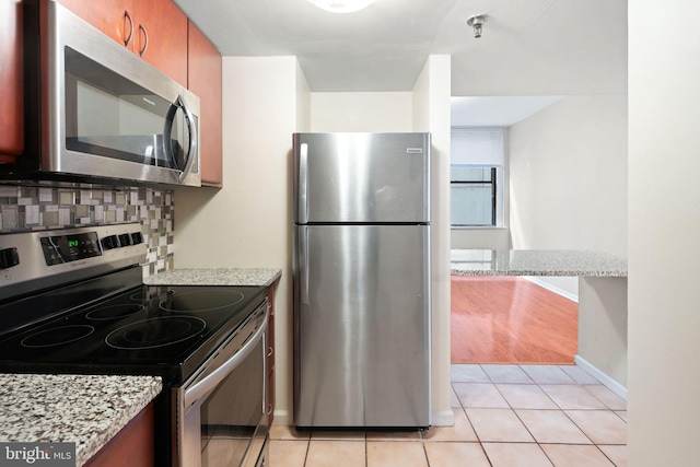 kitchen with light stone countertops, appliances with stainless steel finishes, tasteful backsplash, and light tile patterned flooring