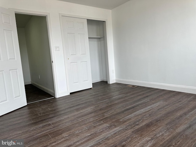 unfurnished bedroom featuring dark hardwood / wood-style floors and a closet