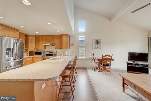 kitchen with lofted ceiling with beams, sink, appliances with stainless steel finishes, a kitchen bar, and kitchen peninsula