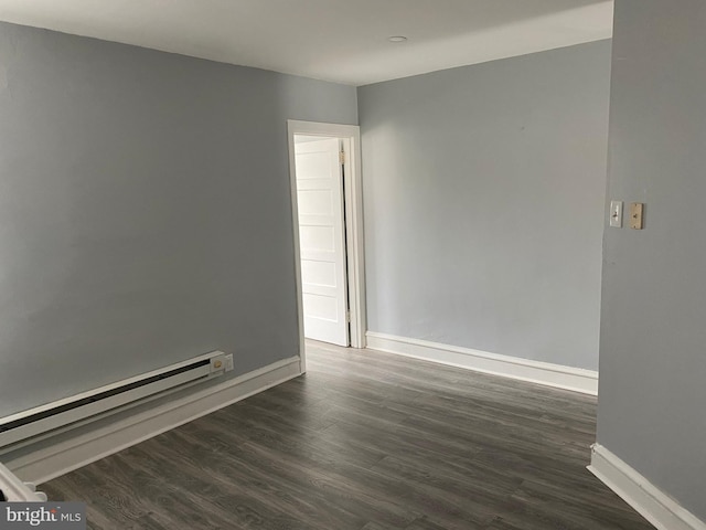 unfurnished room with dark hardwood / wood-style flooring and a baseboard heating unit