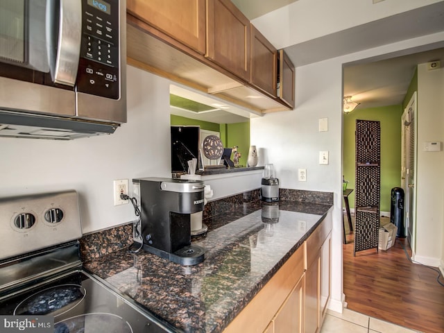 kitchen with light tile patterned floors, range, and dark stone counters