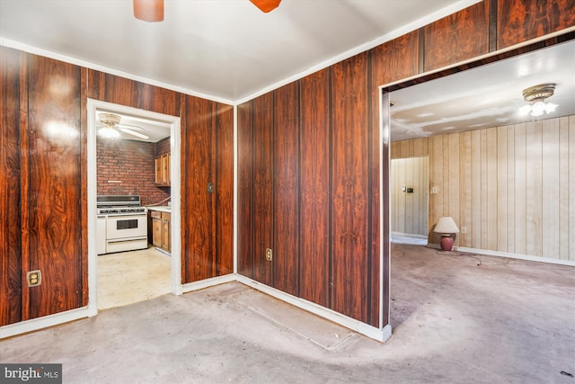 kitchen featuring ceiling fan, wooden walls, and white gas stove