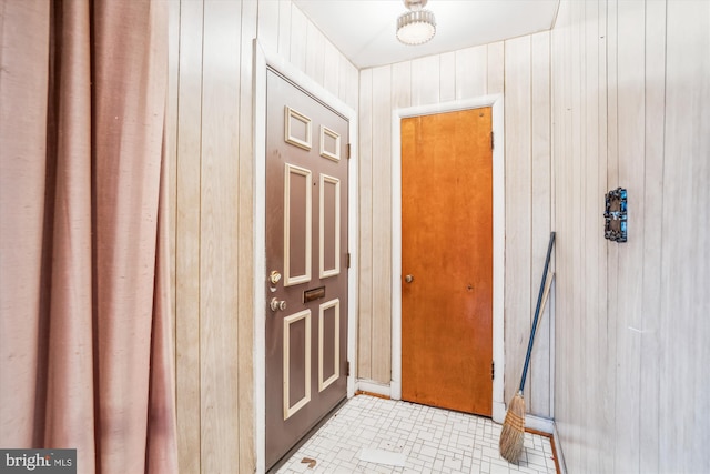 doorway to outside with light tile patterned flooring and wooden walls