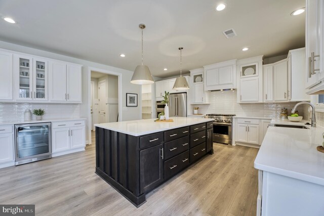 kitchen with high end appliances, a center island, white cabinetry, and wine cooler