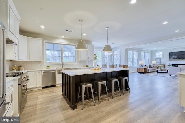 kitchen with white cabinets, stainless steel appliances, a center island, and pendant lighting