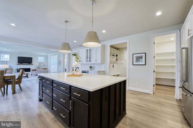 kitchen with white cabinetry, a fireplace, light hardwood / wood-style flooring, high end refrigerator, and pendant lighting