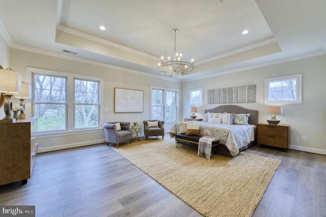 bedroom featuring wood-type flooring, a raised ceiling, a chandelier, and crown molding