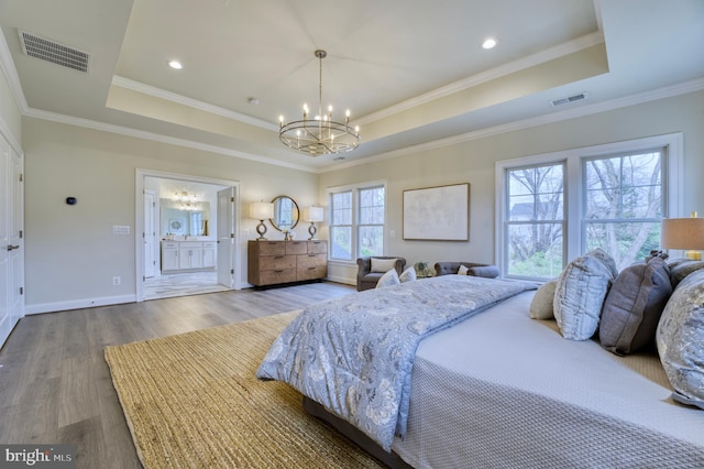 bedroom with wood-type flooring, ensuite bath, a chandelier, and a tray ceiling