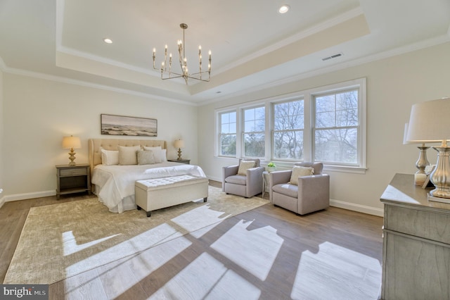 bedroom with a notable chandelier, light wood-type flooring, crown molding, and a tray ceiling