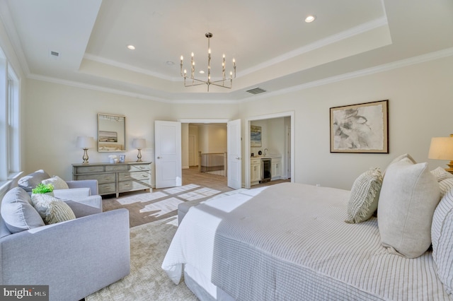 bedroom featuring ensuite bath, a tray ceiling, crown molding, and a chandelier