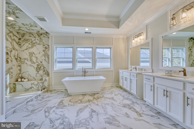 bathroom with ornamental molding, a raised ceiling, vanity, and a bathing tub