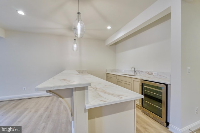 kitchen with sink, decorative light fixtures, a kitchen breakfast bar, light hardwood / wood-style flooring, and wine cooler