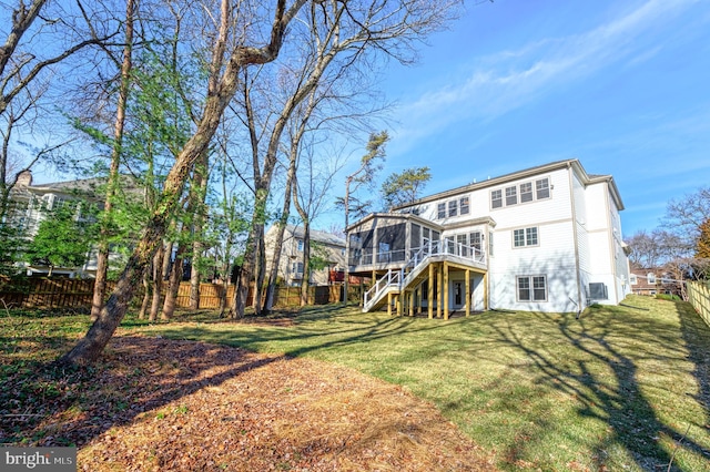 rear view of house featuring a deck, a lawn, and a sunroom