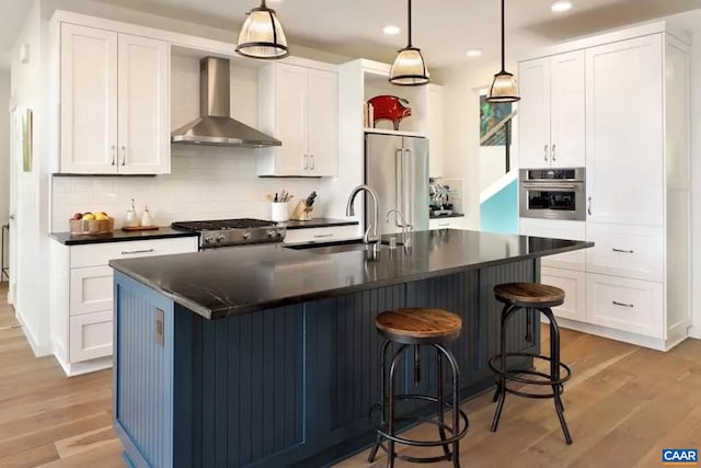 kitchen with white cabinets, wall chimney exhaust hood, decorative light fixtures, and appliances with stainless steel finishes