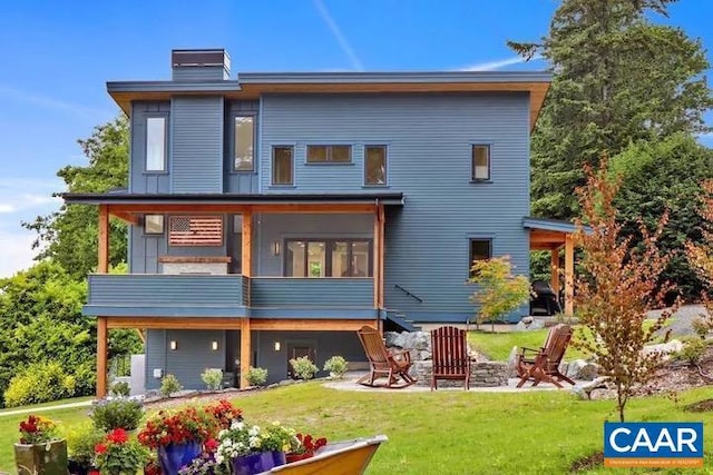 back of property featuring a sunroom, a yard, and a fire pit