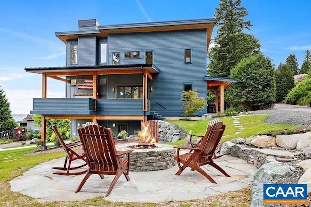 back of house with a fire pit, a yard, and a patio