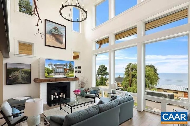 living room featuring a towering ceiling, wood-type flooring, and an inviting chandelier