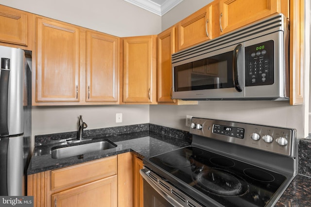 kitchen with dark stone countertops, stainless steel appliances, crown molding, and sink