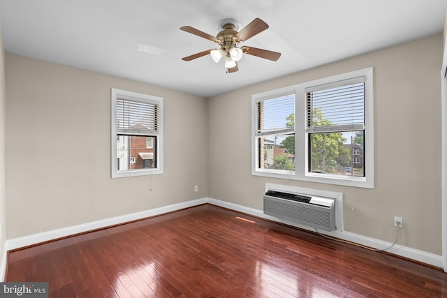 spare room featuring dark hardwood / wood-style flooring, a wall unit AC, and plenty of natural light