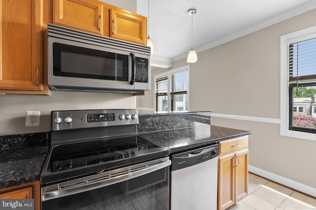 kitchen featuring ornamental molding, dark stone counters, stainless steel appliances, pendant lighting, and light tile patterned flooring