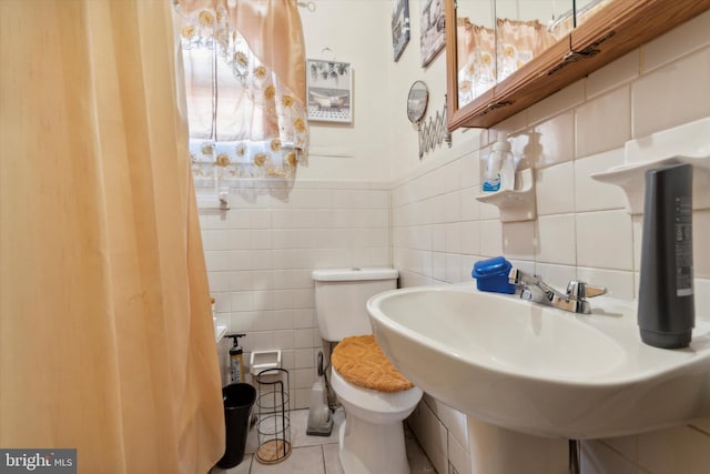 bathroom featuring tile patterned floors, sink, tile walls, and toilet