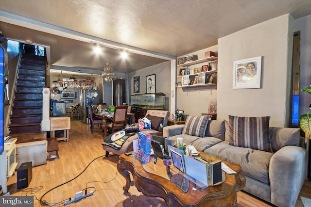 living room featuring built in shelves, a textured ceiling, light hardwood / wood-style floors, and ceiling fan